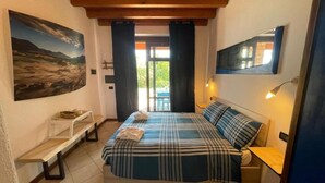 Un dormitorio con cama, un banco, un cuadro, un espejo y una ventana con cortinas.