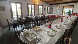 Una larga mesa de comedor con sillas, manteles blancos y centros de mesa.