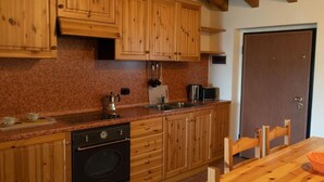 Una cocina con armarios de madera, una encimera, un horno, un fregadero y una mesa de comedor con sillas.