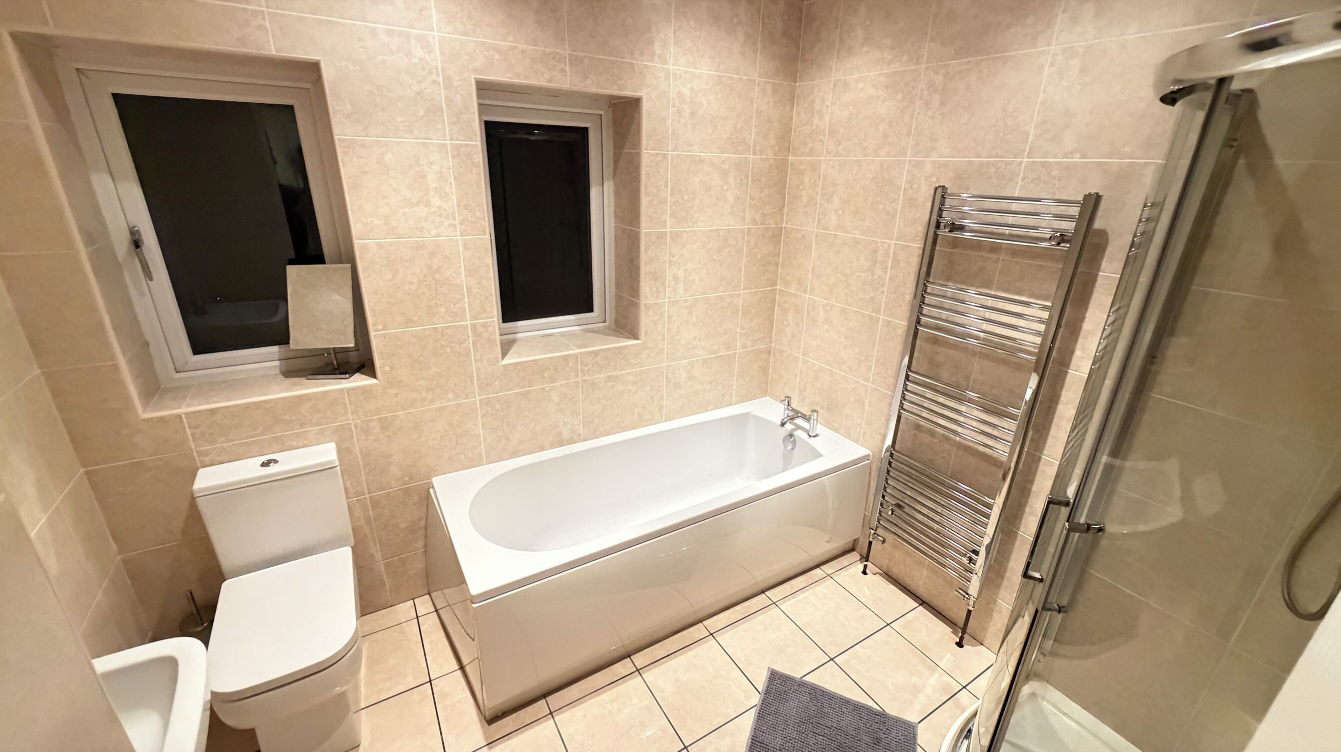 Un baño con bañera, inodoro y cabina de ducha de cristal.
