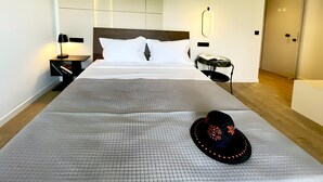 Een hotelkamer met een groot bed, een nachtkastje, een lamp, een koffer en een deur.