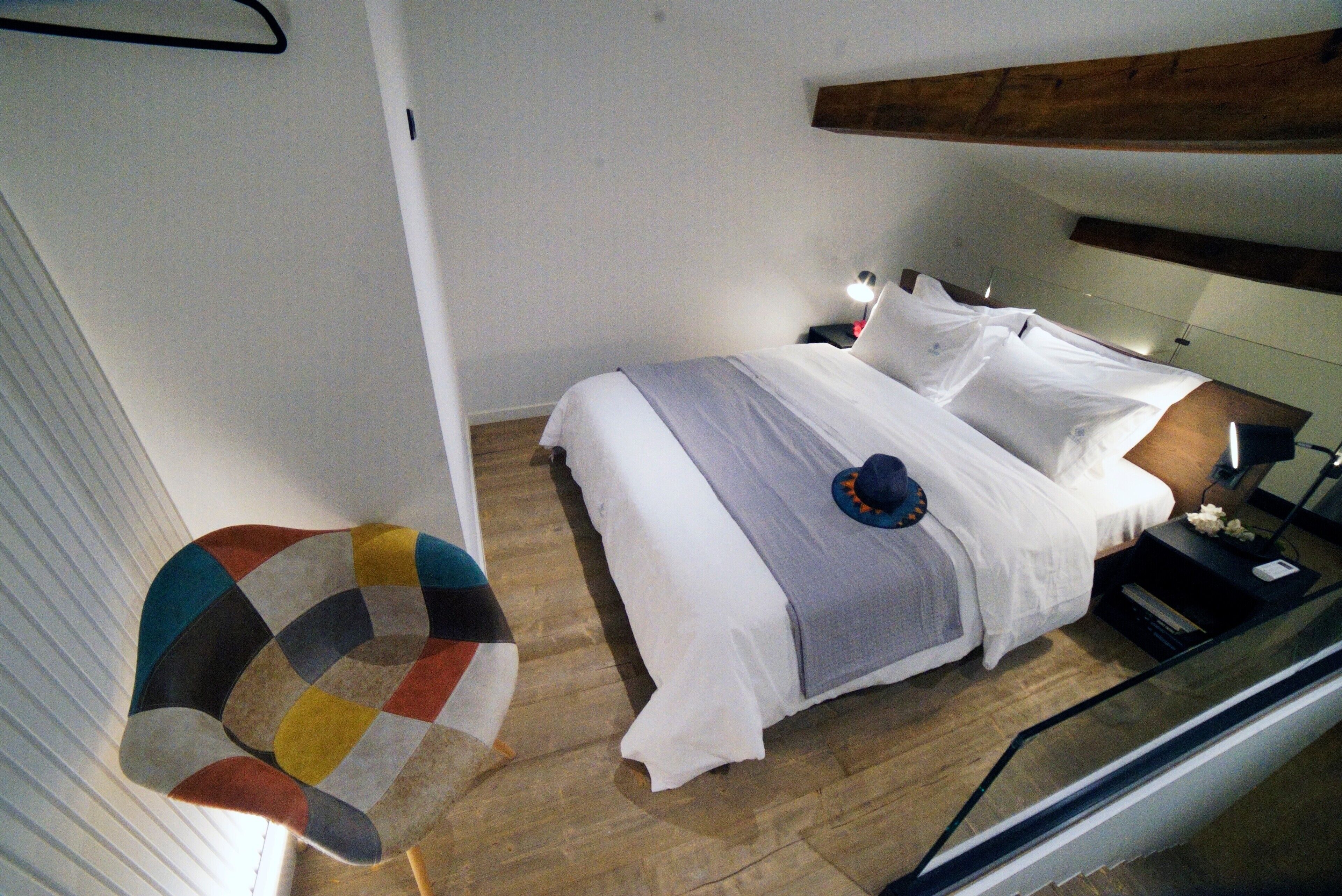 Ein Schlafzimmer mit einem Bett, einem Nachttisch, einer Lampe und einem Sessel.