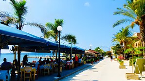 Ein Restaurant am Meer mit Außenbereich, Palmen und Meerblick.