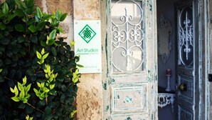 Eine Tür mit dekorativem Metalldekor, ein Schild mit der Aufschrift 'Art Studios' und eine Wand mit Grünpflanzen.