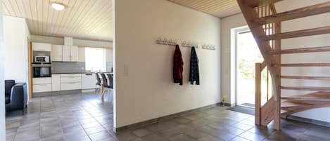 A spacious kitchen with modern appliances, a dining area with chairs, and a wooden staircase.