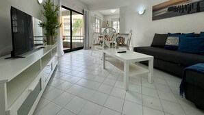 Ein modernes Wohnzimmer mit Flachbildfernseher, einer Couch, einem Couchtisch und einem Essbereich mit Stühlen und einem Tisch.