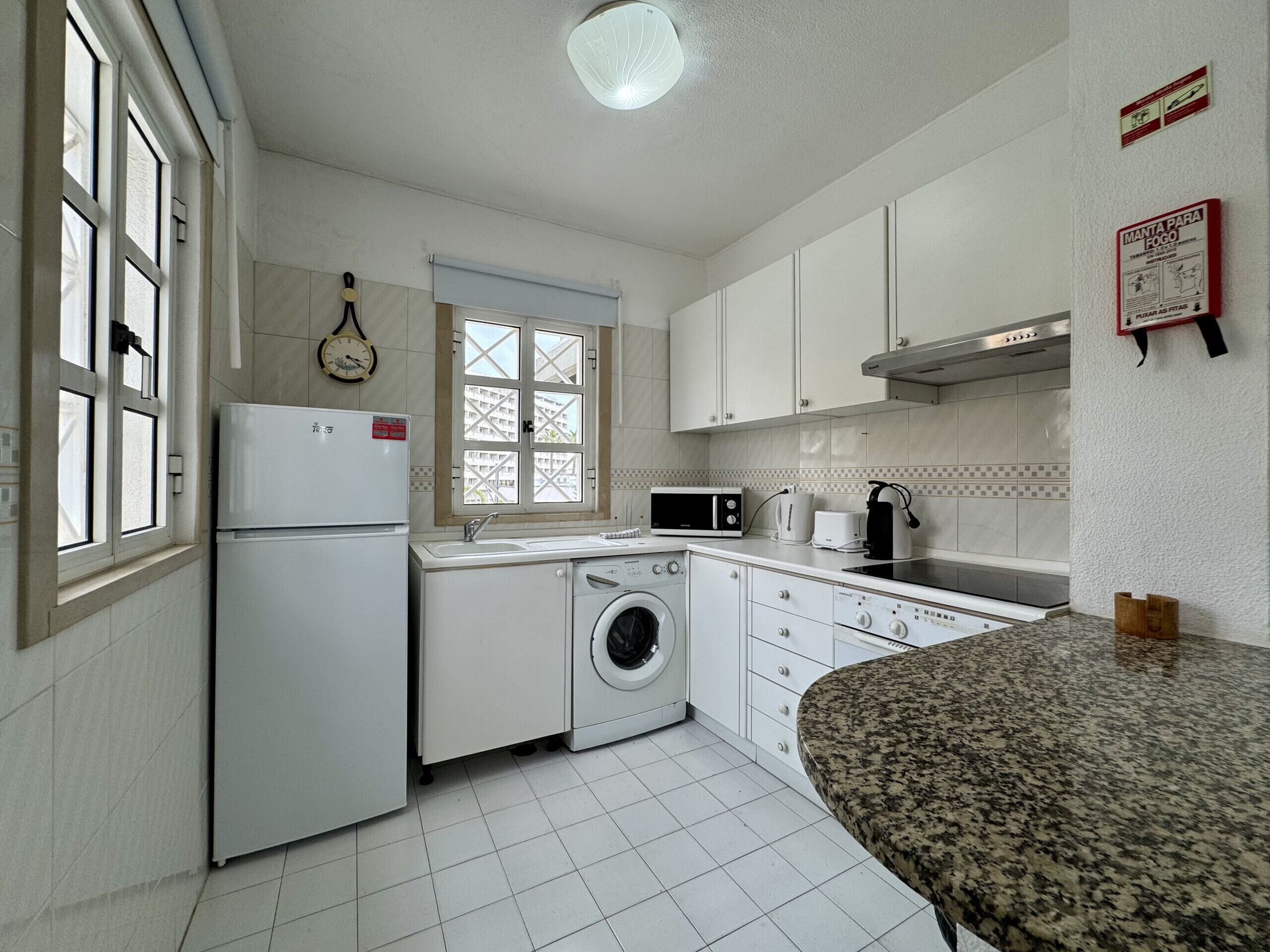 Una cocina compacta equipada con refrigerador, lavadora, microondas y pileta.