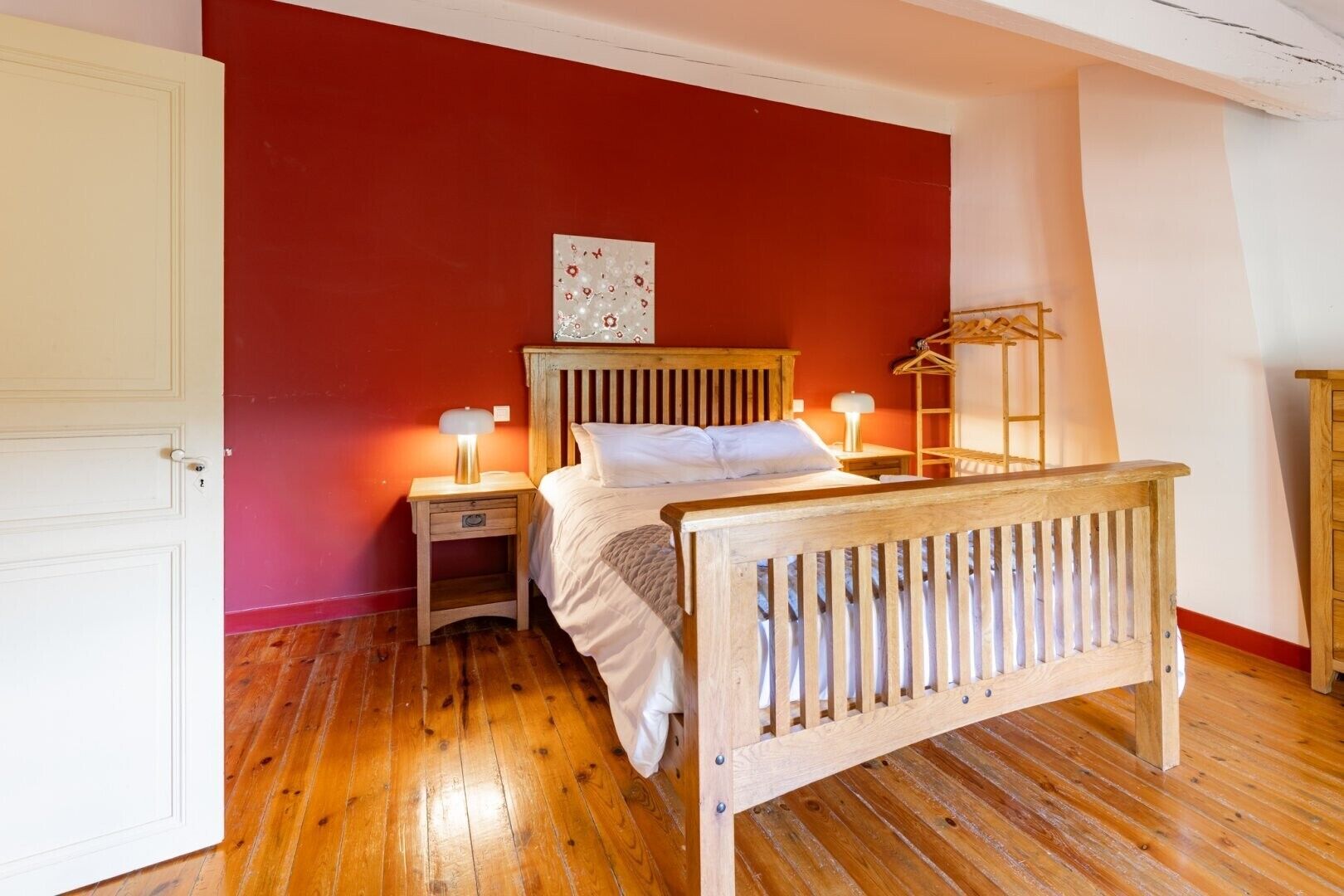 Une chambre à coucher avec un lit en bois, une table de chevet, une commode et une étagère fixée au mur.
