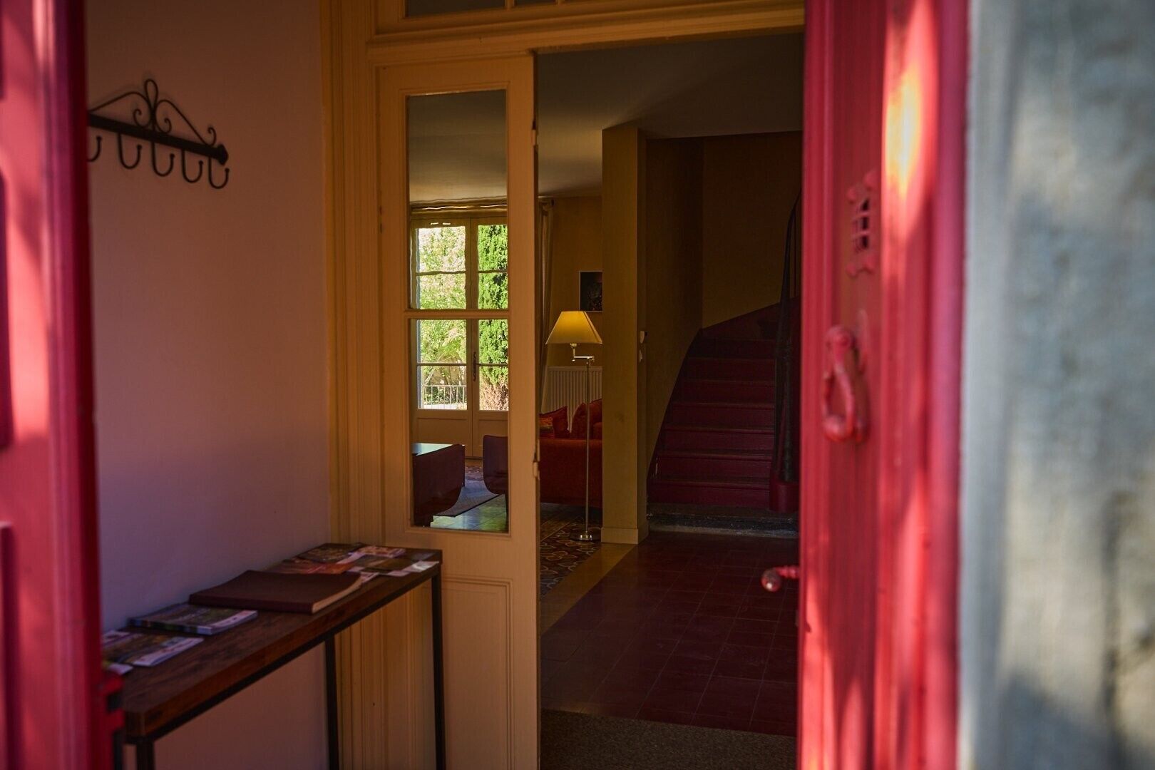Un couloir avec un escalier, une porte dotée d’une poignée et une fenêtre donnant sur un paysage verdoyant.