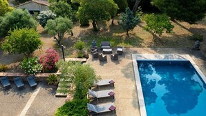 Luftaufnahme eines Poolbereichs mit Liegestühlen und einem kleinen Garten.
