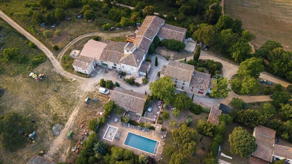 Vista aérea de una propiedad con varias edificaciones, una piscina y follaje circundante.