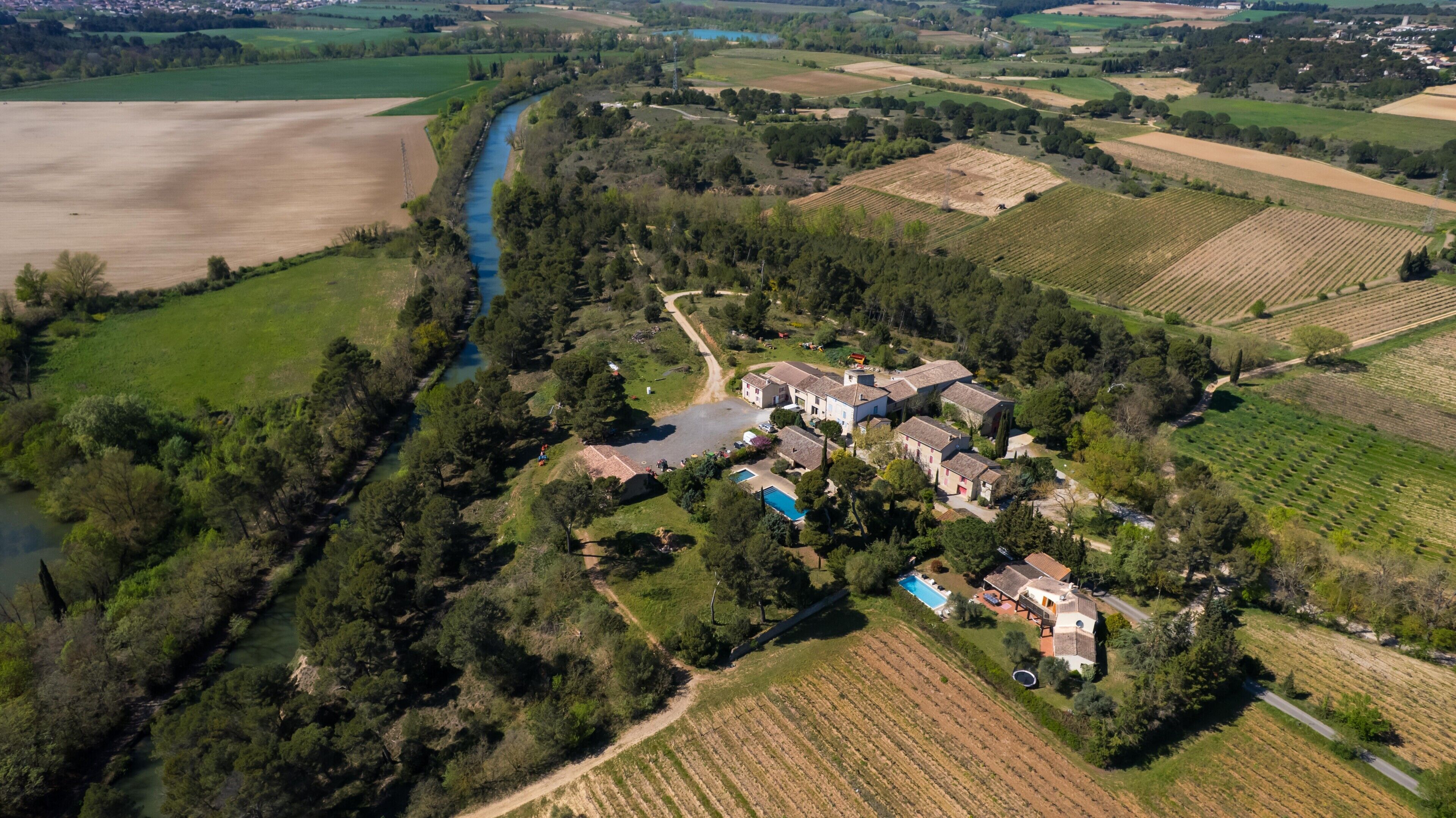 Vista aérea de una propiedad rural con piscina, varias construcciones y campos agrícolas circundantes.