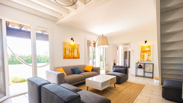 A modern living room with a sofa, ottoman, coffee table, and artwork. - Bastide des Vignes: Private Pool and Tranquility on a Vineyard Estate (Trèbes)