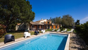 A swimming pool with lounge chairs, a building with a tiled roof, and surrounding greenery. - Bastide des Vignes: Private Pool and Tranquility on a Vineyard Estate (Trèbes)