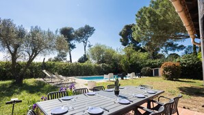 An outdoor dining area with a table set for six, surrounded by chairs, overlooking a swimming pool and lush greenery. - Bastide des Vignes: Private Pool and Tranquility on a Vineyard Estate (Trèbes)