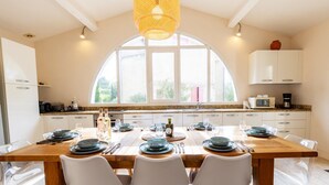 Una cocina moderna con una isla grande, armarios blancos y un amplio ventanal.