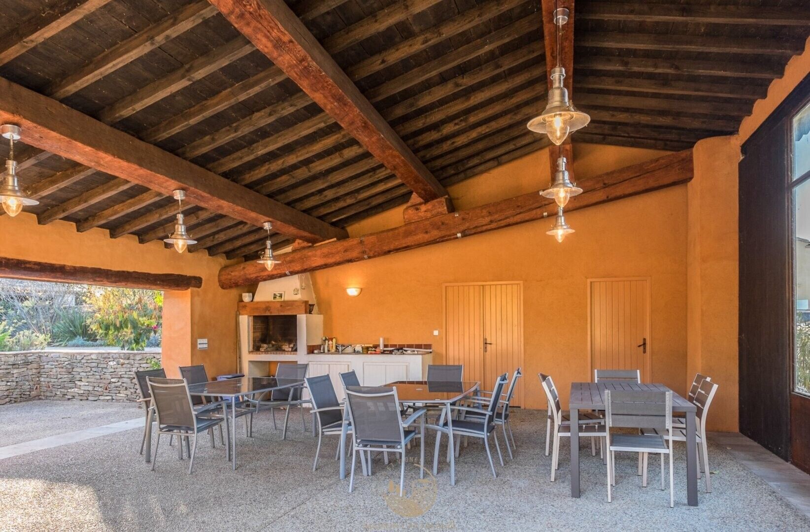 Un patio al aire libre con un muro de piedra, una parrilla y un área de estar con mesas y sillas.
