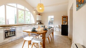 Una cocina moderna con comedor, ventanas amplias y una lámpara colgante.