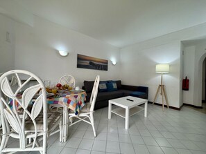 Sala de estar com mesa de jantar posta, sofá, mesa de centro e abajur.