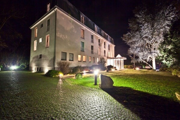 A large, multi-story building with a paved driveway and a well-lit entrance. - Select Hotel Silence Garden (Cologne)