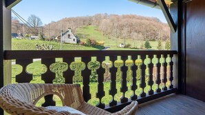 Une chaise en osier sur une terrasse en bois, offrant une vue sur un paysage rural.