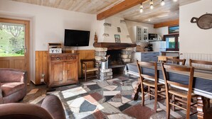 Un intérieur rustique avec une cheminée en pierre, des meubles en bois, un téléviseur à écran plat et un coin cuisine.