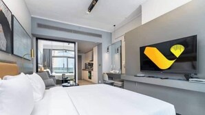A modern hotel room with a large bed, a television, and a view of the city. - Vogue| Downtown close to Burj Khalifa | Dubai Mall (Dubai)