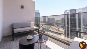 A balcony with a sofa, a small round table, and a view of a cityscape. - Vogue| Downtown close to Burj Khalifa | Dubai Mall (Dubai)