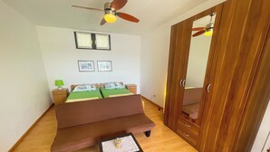 Ein Schlafzimmer mit Bett, einer Sitzbank, einem kleinen Tisch, einem Kleiderschrank und einem Deckenventilator.