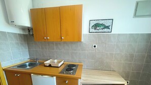 Eine kompakte Küche mit Holzschränken, einer Spüle, einem Geschirrspüler und einer kleinen Arbeitsfläche mit Herd.