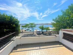 Une terrasse avec vue sur la mer, des sièges extérieurs et une rambarde.