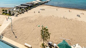 Een strand met een pier, een zwembad en een restaurant genaamd MIRAI.