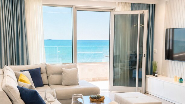 Een moderne woonkamer met een eetgedeelte, grote ramen en uitzicht op zee.