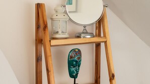 Een houten plank met een spiegel, een decoratief masker en een klein beeldje.