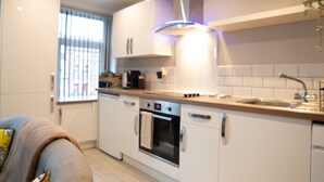Een moderne keuken met witte kasten, een ingebouwde oven en een roestvrijstalen afzuigkap.