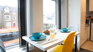 Een moderne keuken met een ontbijt gedekte eettafel, met een croissant, sinaasappelsap en een blauwe kom.