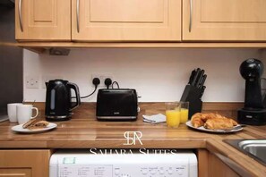 Eine Küche mit Holzausstattung, einer Kaffeemaschine, einem Toaster und einem Glas Orangensaft.