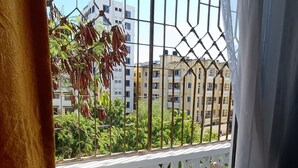 A balcony with a white lattice railing, two cushioned chairs, and a view of multi-story buildings and greenery. - Greyline luxe Bamburi. O743 for 379 then I35. (Mombasa)