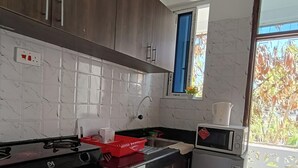 A modern kitchen with dark wooden cabinets, a black countertop, and a stainless steel refrigerator. - Greyline luxe Bamburi. O743 for 379 then I35. (Mombasa)