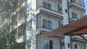 A multi-story building with balconies, a signboard for a gas delivery company, and a tree in the foreground. - Greyline luxe Bamburi. O743 for 379 then I35. (Mombasa)