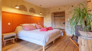 Une chambre à coucher avec un lit, une tête de lit en bois, une table de chevet et une plante en pot.