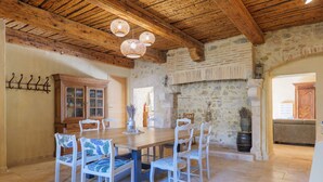 A dining area with a wooden table and chairs, a stone wall, and a wooden ceiling. - Guest Room “L’Aphyllanthe” with Large Shared Courtyard and Wi-Fi (Saint-Remèze)