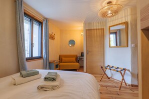 Une chambre à coucher avec un lit, une chaise, un miroir et une petite table.
