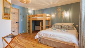 Une chambre avec un lit superposé, une armoire en bois, un miroir et des attrape-rêves accrochés au mur.