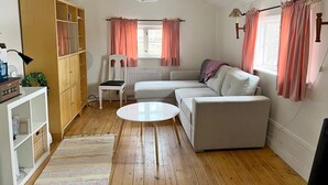 Ein gemütliches Wohnzimmer mit einem weißen Sofa, einem runden Couchtisch und einer Holzkabine.