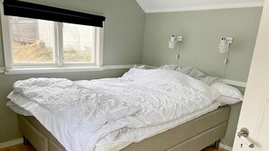 Ein Bett in einem Zimmer mit Fenster, einer weißen Tür und einem weißen, flauschigen Teppich auf dem Boden.