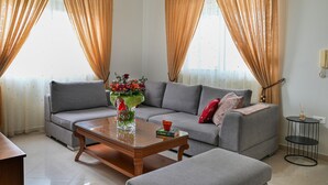 Una sala de estar con un sofá gris, una mesa de centro de madera y un florero con flores.