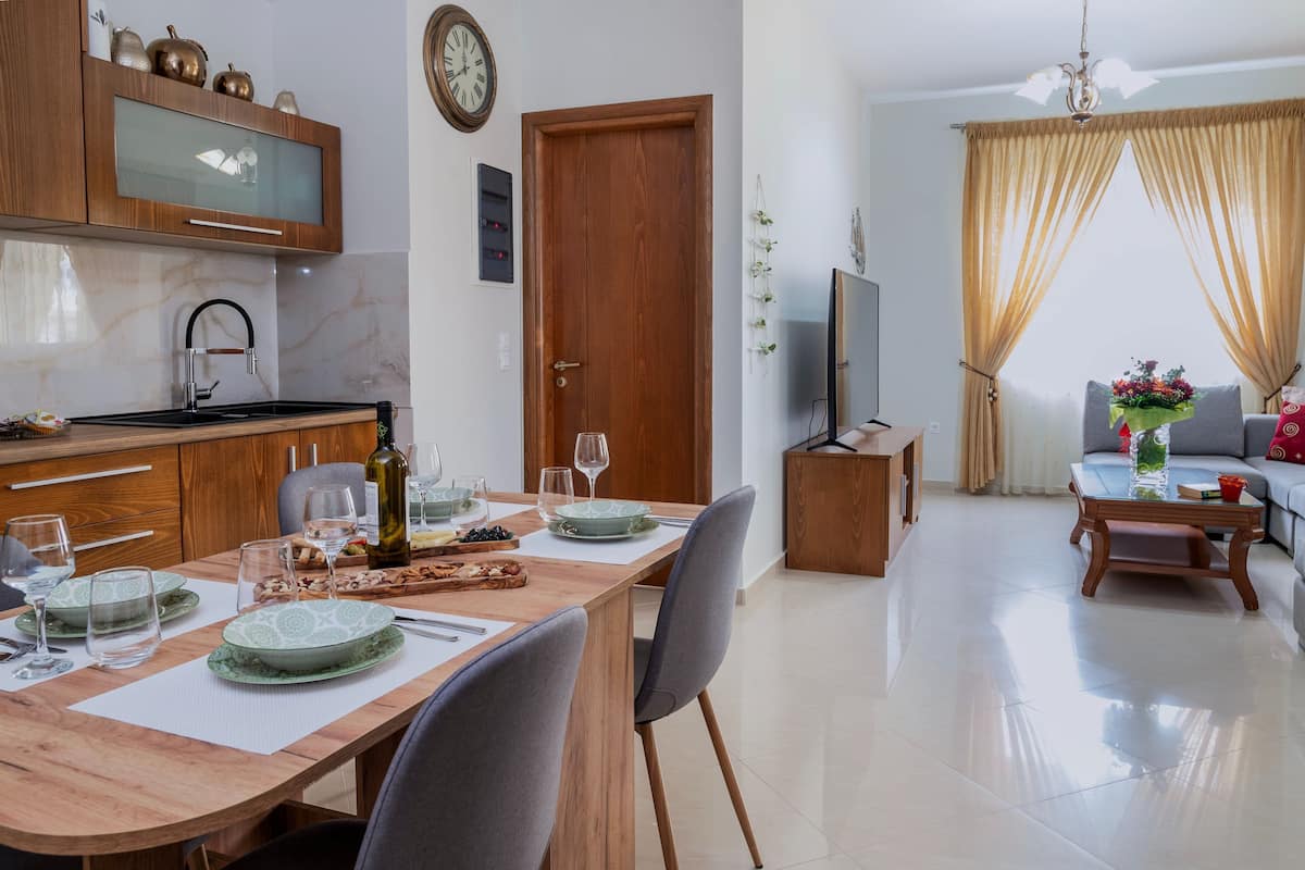 A modern kitchen with wooden cabinets, a built-in oven, and a dining area with a table set for four.