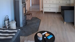 A living room with a fireplace, TV, sofa, and a dining area with a table and chairs. - Holiday Home Apfelblüte in Swedish Style on Pellworm (Pellworm)