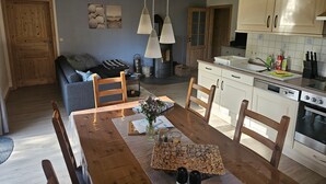 A cozy kitchen with wooden cabinets, a dining table, chairs, a stove, and a fireplace. - Holiday Home Apfelblüte in Swedish Style on Pellworm (Pellworm)